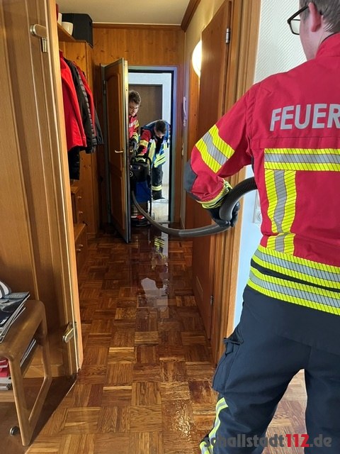 Feuerwehrangehörige saugen Wasser aus einem überfluteten Flur