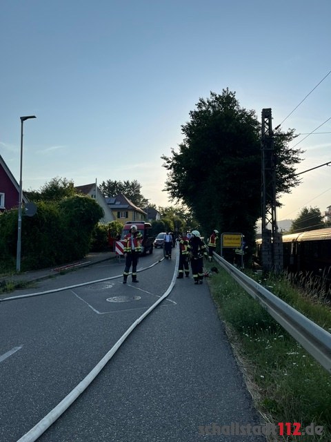 Feuerwehrangehörige und Löschleitung neben dem stillstehenden Zug